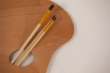 Wooden palette and paint brushes on white backgroundの写真素材