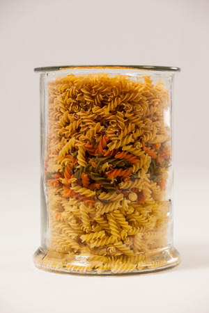 Girandole pasta in a glass container against white backgroundの写真素材