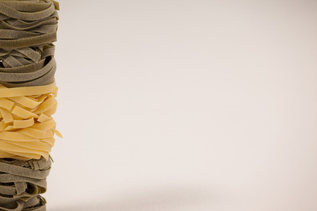 Roll of tagliatelle pasta on white background