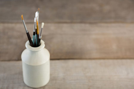 Various paintbrush in a ceramic jar on wooden surfaceの写真素材