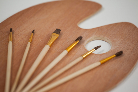 Wooden palette and paint brushes on wooden tableの写真素材