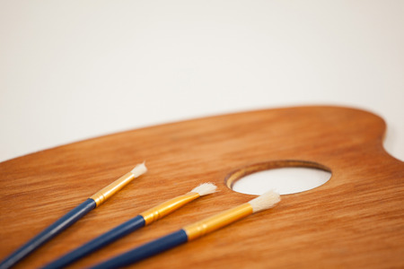 Wooden palette and paint brushes on wooden tableの写真素材