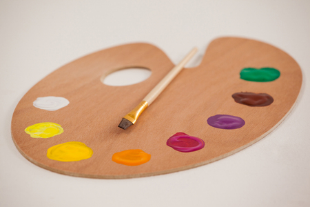 Palette with multiple colors and paint brush on wooden tableの写真素材