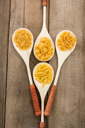 Spoons filled with varieties of pasta on white backgroundの写真素材