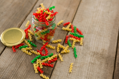 Glass jar filled with tri-colored rotini pasta on wooden backgroundの写真素材