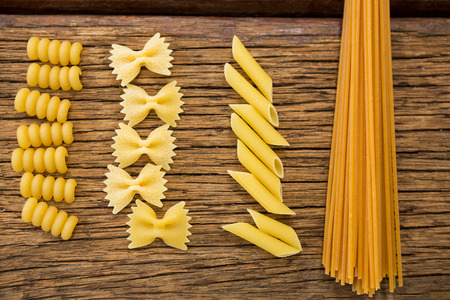 Various pasta arranged in a row on wooden surfaceの写真素材
