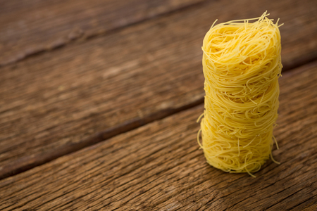 Stack of capellini pasta on wooden surface