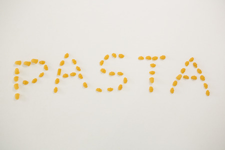 Various pasta arranged in shape of pasta text on white backgroundの写真素材