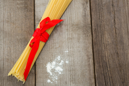 Bundle of raw spaghetti and flour on wooden surfaceの写真素材