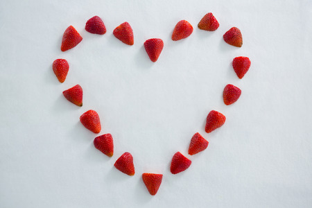 Red strawberries forming a heart shape on white backgroundの写真素材