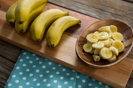Overhead of banana and slices of banana in plate kept on chopping boardの写真素材
