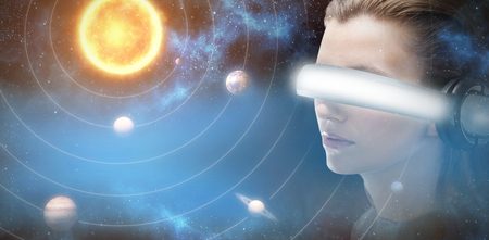 Close up of brunette experiencing virtual reality simulator against graphic image of planets and sun...