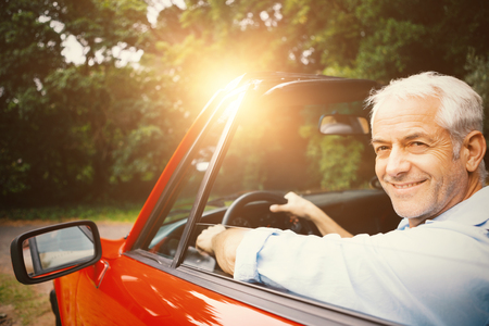 Smiling happy handsome man driving red carの写真素材