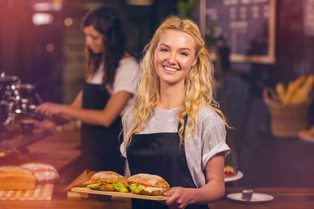 Graphic image of flare against portrait of pretty waitress holding tray with sandwichesの写真素材