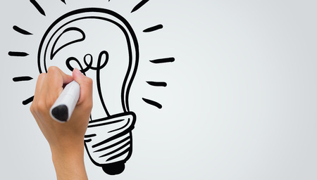 Light bulb against female hand writing with markerの写真素材
