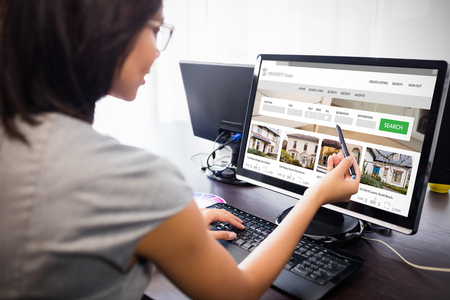 Composite image of property web site against woman watching her computerの写真素材