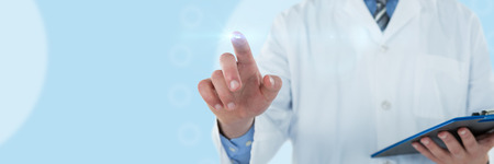 Doctor holding clipboard while touching transparent interface against medical iconの写真素材