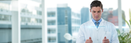 Concentrated male doctor using futuristic glass against laptop on desk by glass window in officeの写真素材