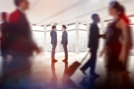 Businessmen talking against windows overlooking cityの写真素材
