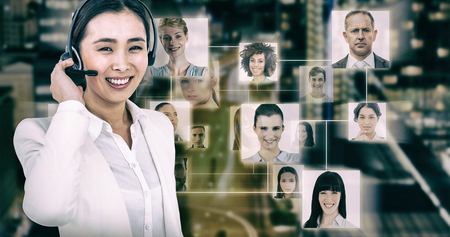 Smiling businesswoman using headset against glowing road amidst building in city at nightの写真素材