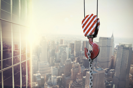 Studio Shoot of a crane lifting hook against image of a city landscape on a sunny dayの写真素材
