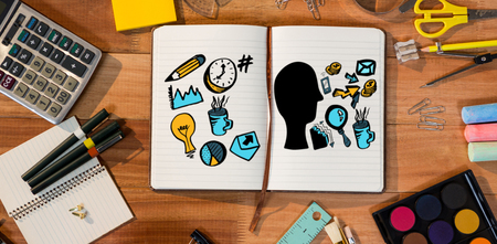 Composite image of human representation amidst different business symbols against open diary with various stationeryの写真素材