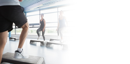 Trainer stepping with aerobics class in gym