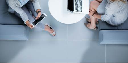 White background with vignette against businesswomen using laptop and digital tabletの写真素材