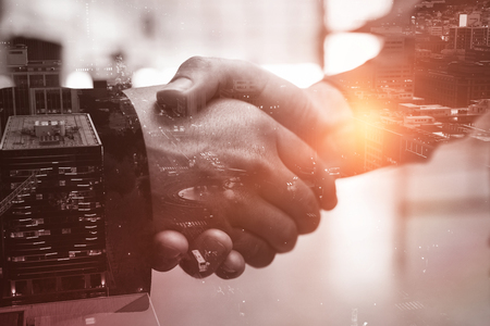 Glowing roads by building in city against close up of a handshakeの写真素材