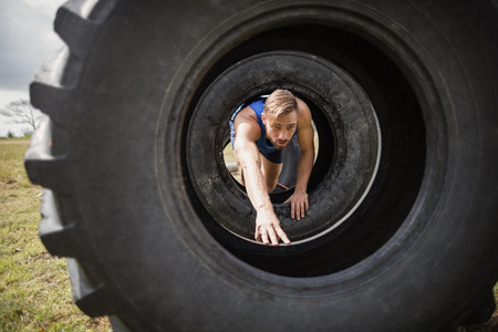 Man crawling through the tire during obstacle course in boot campの写真素材