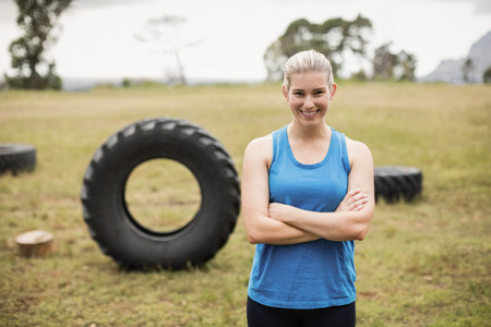 Fit woman standing with arms crossed in boot camp on a sunny dayの写真素材