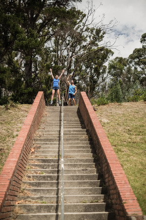 Happy fit man and woman standing near staircase during obstacle course in boot camp