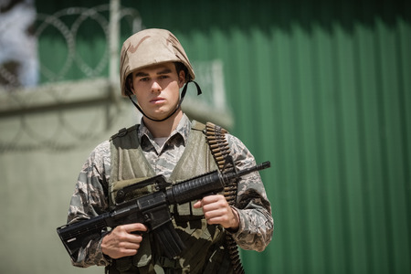 Military soldier standing with a rile in boot camp