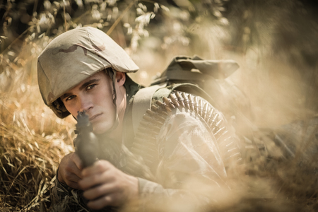 Portrait of military soldier aiming with a rifle in boot camp