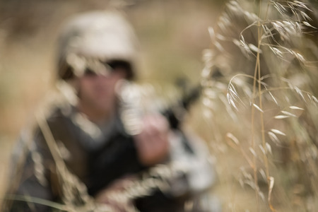 Military soldier hiding in grass while guarding in boot campの写真素材
