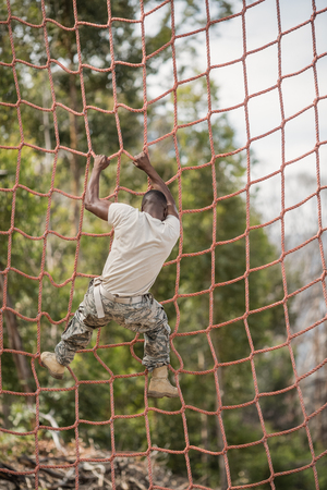 Military soldier climbing net during obstacle course in boot campの写真素材