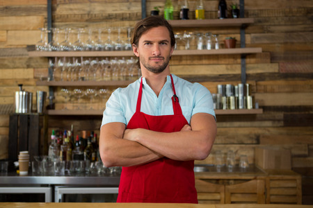 Portrait of male barista standing arms crossed in coffee shopの写真素材