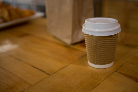 Close-up of disposable coffee cup on table in cafeの写真素材