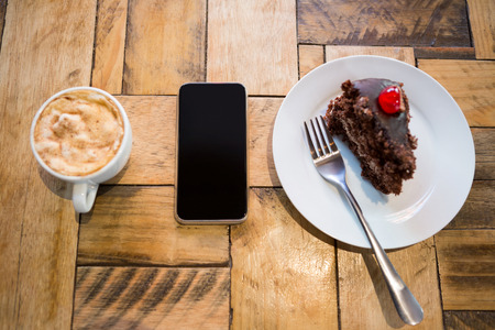 Overhead shot of smart phone with pastry and coffee cup on tableの写真素材