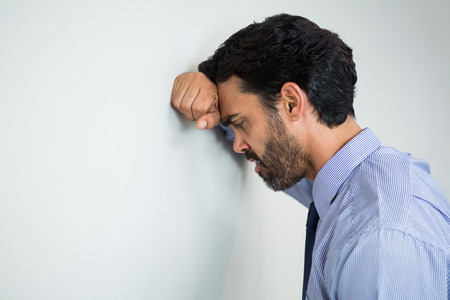Worried and stressed businessman with hand on head at conference centreの写真素材