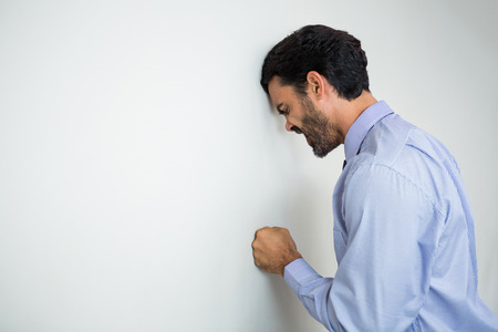 Worried and stressed businessman with hand on wall at conference centreの写真素材