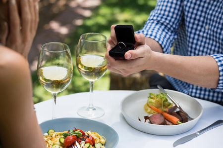 Cropped image of man showing engagement ring to woman at outdoor restaurantの写真素材