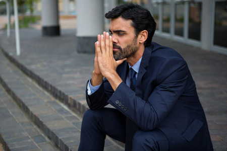 Stressed businessman sitting on steps in conference centreの写真素材