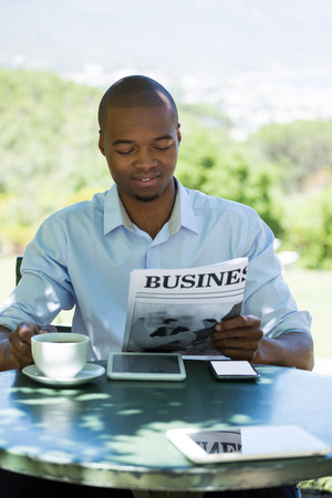 Young businessman reading business newspaper at restaurantの写真素材