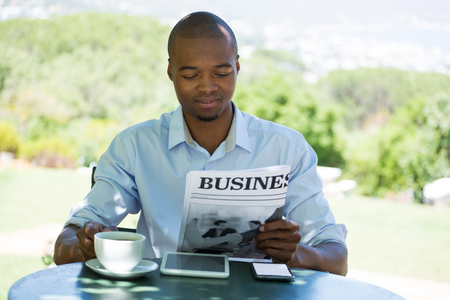 Young man reading business newspaper at restaurantの写真素材