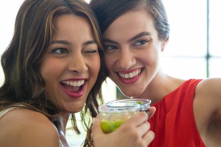 Close-up of cheerful young women toasting drinks in restaurantの写真素材