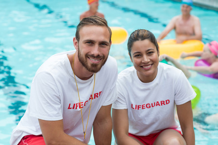 Portrait of male and female lifeguards crouching at poolsideの写真素材