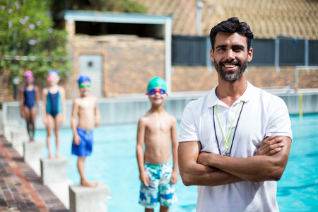 Portrait of instructor while children standing on starting block