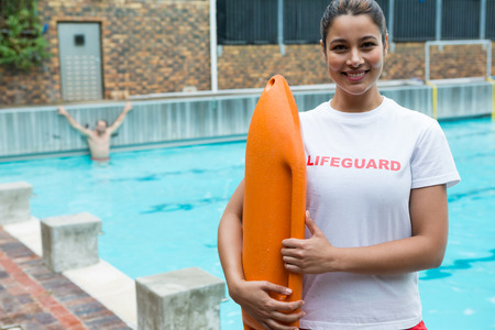Portrait of lifeguard standing with rescue buoy at poolsideの写真素材