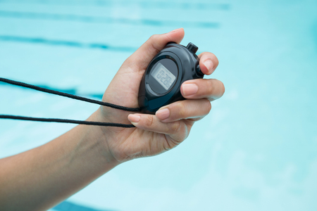 Close-up of coach hand holding stopwatch at poolside
